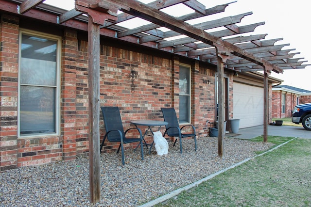 view of patio / terrace with an attached garage and a pergola