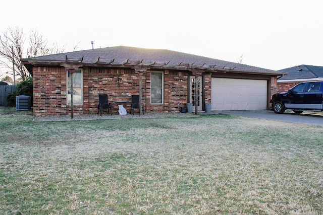 ranch-style home featuring central AC, concrete driveway, a front yard, an attached garage, and brick siding