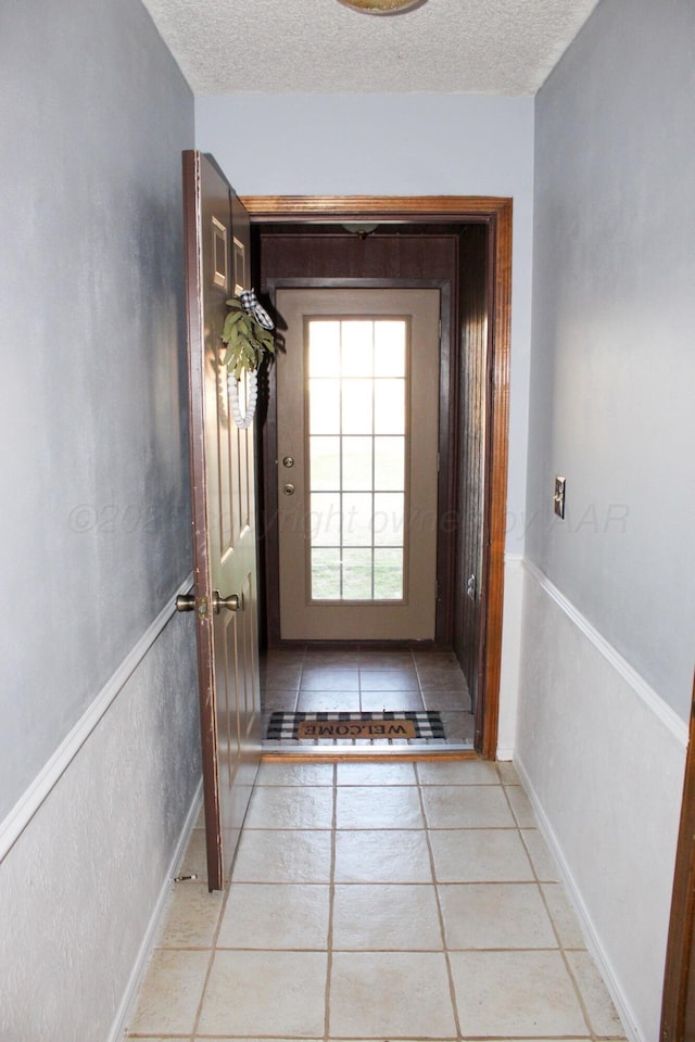 doorway featuring light tile patterned floors and a textured ceiling