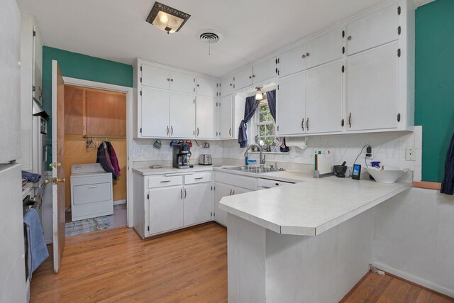 3515 Linda Dr, Amarillo, TX 79109 - kitchen with washer / clothes dryer, light wood-style floors, decorative backsplash, and white cabinetry