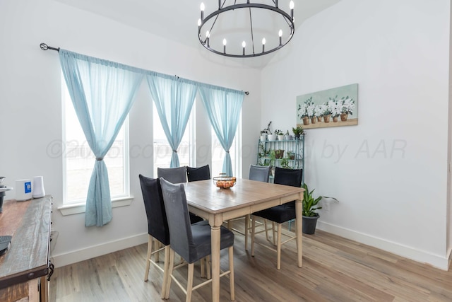 dining area featuring baseboards, wood finished floors, and a notable chandelier