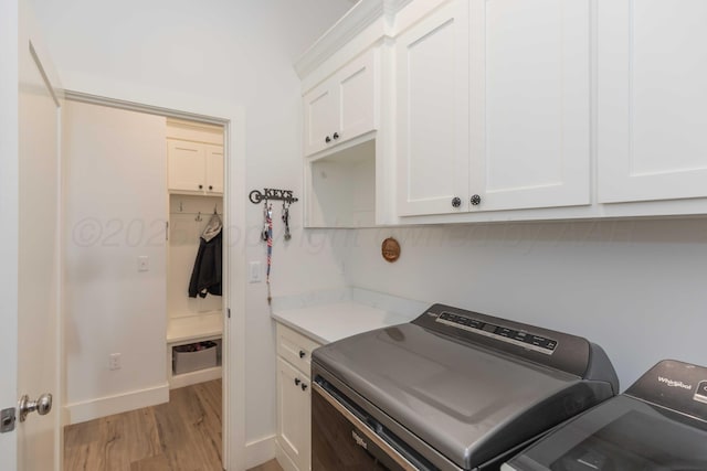 laundry room featuring light wood-style flooring, washer and dryer, cabinet space, and baseboards