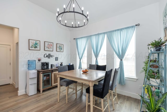 dining area featuring a wealth of natural light, light wood-style floors, a notable chandelier, and baseboards