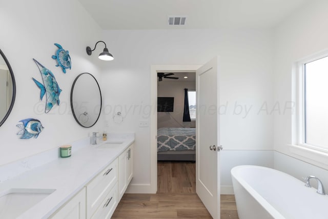 full bath with a sink, connected bathroom, visible vents, a freestanding bath, and wood finished floors