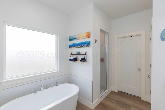 bathroom with a soaking tub, wood finished floors, and a shower stall