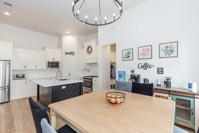 dining space with recessed lighting, a chandelier, a toaster, light wood finished floors, and visible vents
