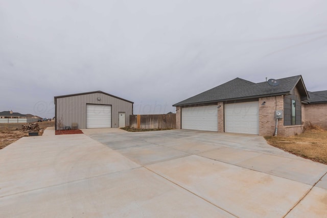 view of side of home featuring fence, a shingled roof, brick siding, and a garage