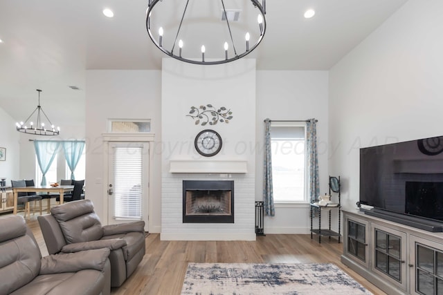 living area with a fireplace, wood finished floors, a chandelier, and a wealth of natural light
