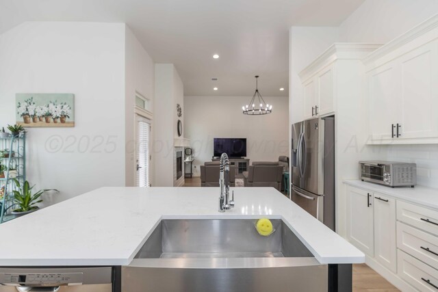 kitchen featuring a sink, light countertops, a toaster, open floor plan, and stainless steel fridge