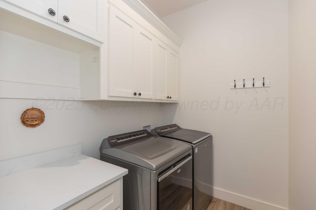 laundry room with washing machine and dryer, cabinet space, baseboards, and light wood-style floors