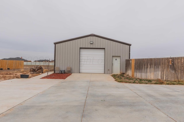 detached garage featuring driveway and fence