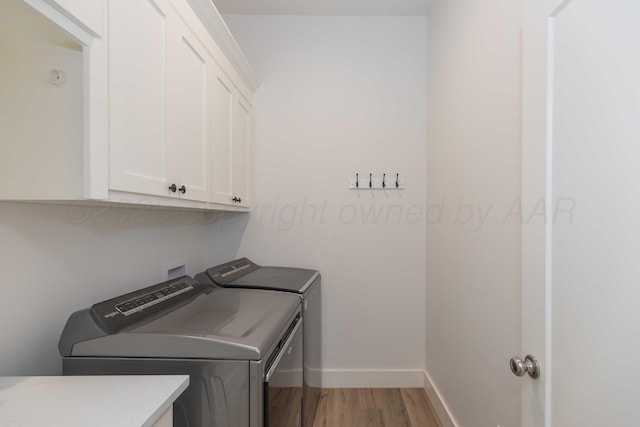 laundry area featuring baseboards, light wood-type flooring, cabinet space, and washing machine and dryer