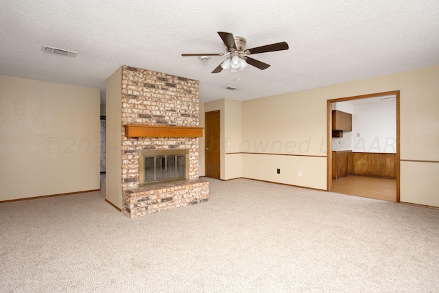 unfurnished living room featuring visible vents, ceiling fan, carpet, a textured ceiling, and a fireplace