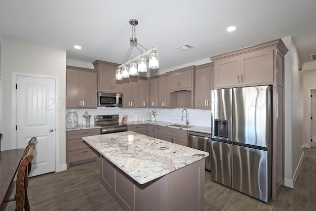 kitchen with a center island, sink, hanging light fixtures, dark hardwood / wood-style flooring, and stainless steel appliances