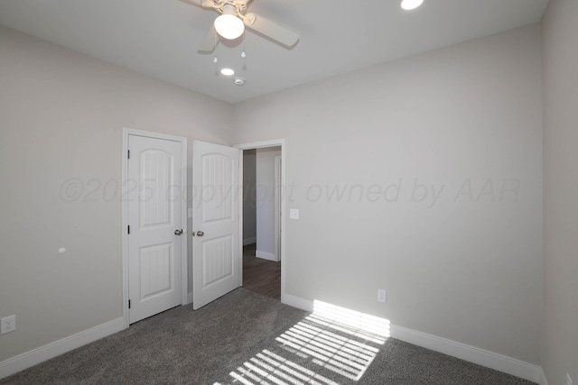 unfurnished room featuring ceiling fan and dark colored carpet