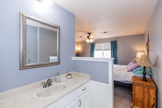 bathroom with ceiling fan, vanity, and a textured ceiling
