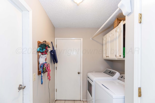 clothes washing area with cabinet space, a textured ceiling, light tile patterned floors, and separate washer and dryer