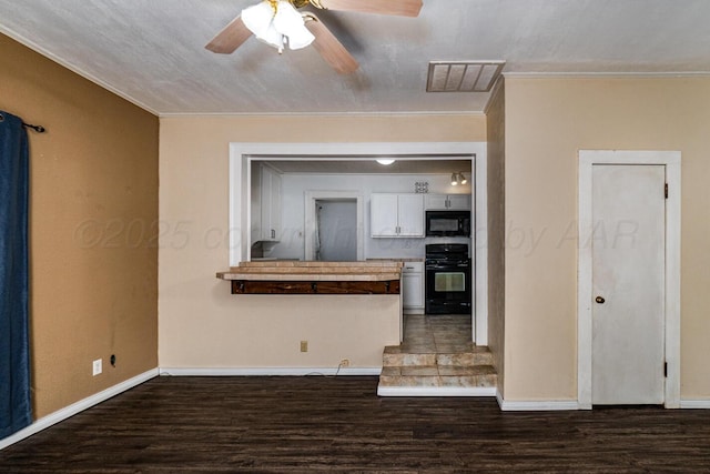 3704 Fountain Ter, Amarillo, TX 79106 - kitchen with range, black microwave, dark wood finished floors, white cabinetry, and ornamental molding