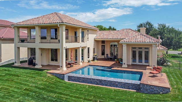 back of property featuring a lawn, french doors, a balcony, a fenced in pool, and a patio area