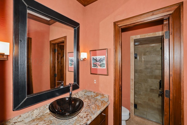bathroom with toilet, vanity, an enclosed shower, and ornamental molding