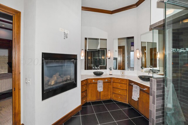 13 Prestwick Ln, Amarillo, TX 79124 - ensuite bathroom featuring crown molding, tile patterned floors, double vanity, a glass covered fireplace, and a shower with door