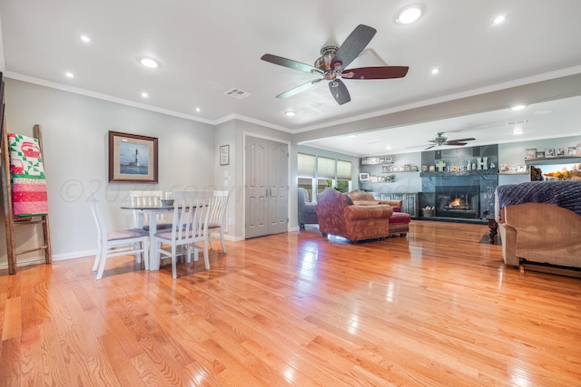 living room featuring crown molding, a fireplace, and light wood-type flooring