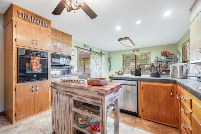 kitchen featuring a wealth of natural light, tile countertops, black appliances, and a barn door