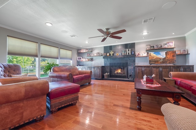 living room with light hardwood / wood-style flooring, ornamental molding, and ceiling fan