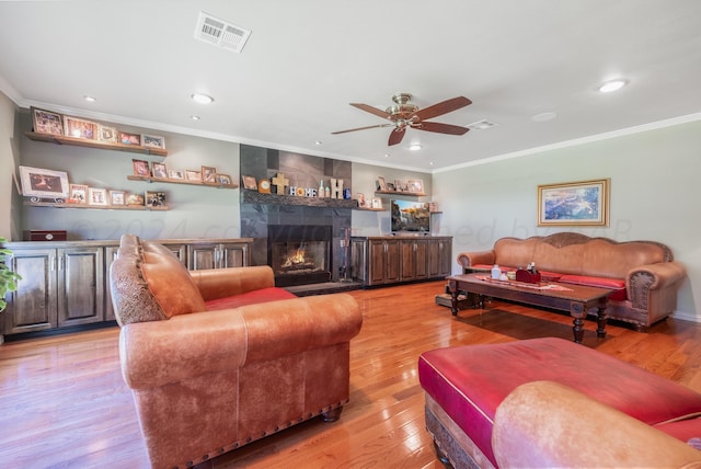 living room with crown molding, ceiling fan, a fireplace, and light hardwood / wood-style floors