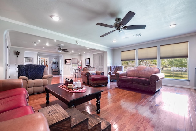 living room with hardwood / wood-style floors, crown molding, and ceiling fan