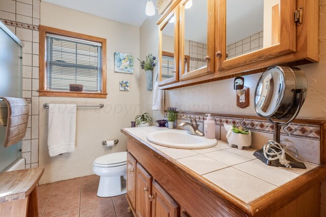 bathroom featuring tasteful backsplash, vanity, toilet, and tile patterned flooring