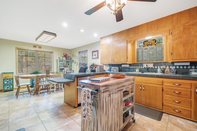 kitchen featuring light tile patterned flooring, a kitchen bar, decorative backsplash, a center island, and ceiling fan