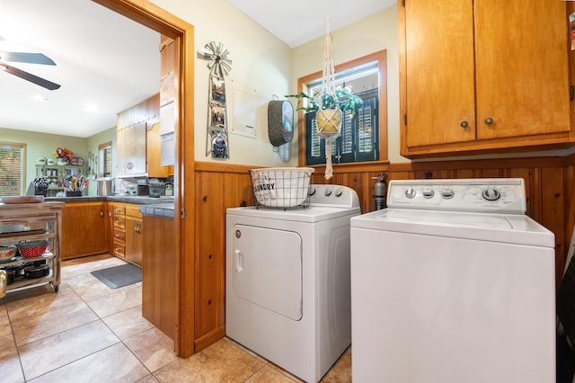 clothes washing area featuring light tile patterned floors, ceiling fan, wooden walls, cabinets, and independent washer and dryer