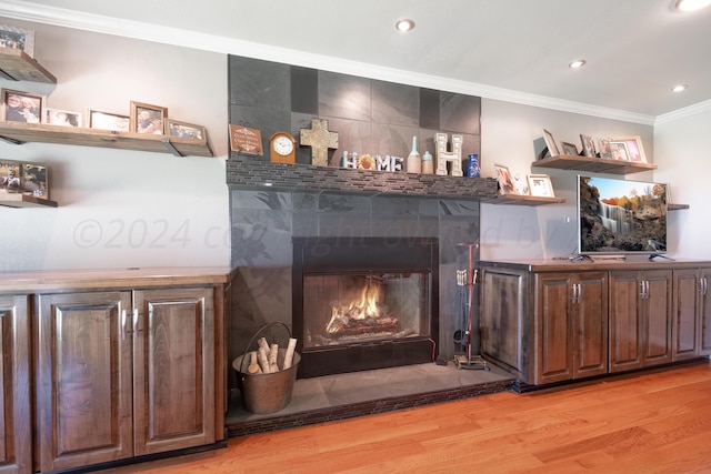 interior details featuring a large fireplace, wood-type flooring, and ornamental molding