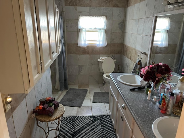 bathroom featuring vanity, tile patterned flooring, a healthy amount of sunlight, and tile walls