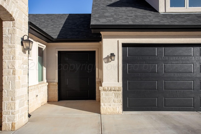 doorway to property with a garage, driveway, a shingled roof, and stucco siding