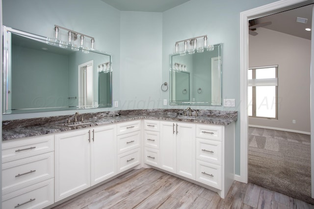 bathroom featuring double vanity, visible vents, wood finished floors, and a sink