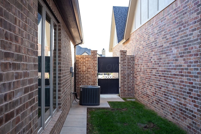 view of property exterior featuring board and batten siding, brick siding, roof with shingles, and central AC