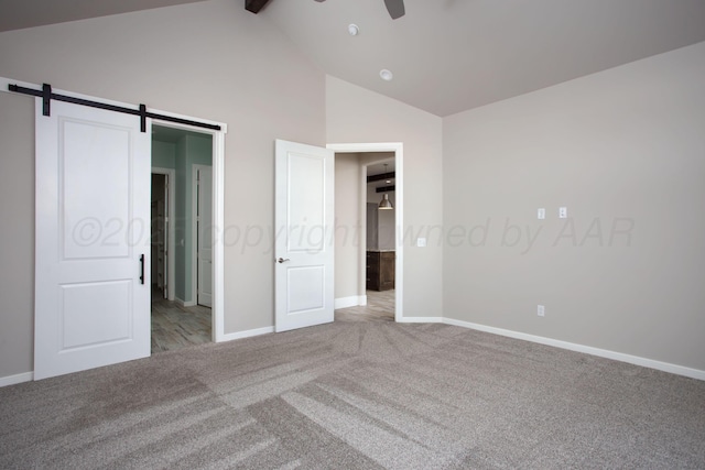 unfurnished bedroom featuring high vaulted ceiling, a barn door, baseboards, carpet flooring, and beam ceiling