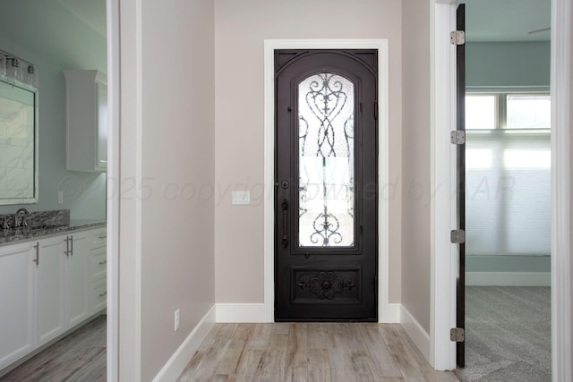 foyer entrance with light wood-type flooring and baseboards