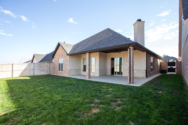 rear view of house featuring a fenced backyard, a chimney, ceiling fan, a yard, and stucco siding