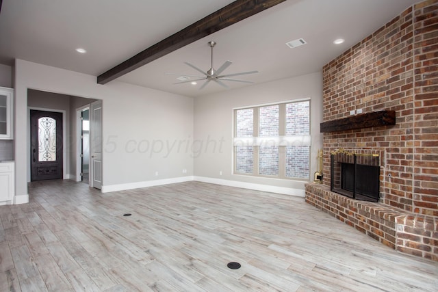 unfurnished living room featuring ceiling fan, beamed ceiling, light wood-style flooring, a fireplace, and visible vents