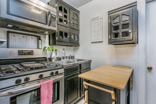 131 S Nelson St, Pampa, TX 79065 - kitchen featuring stainless steel appliances, a sink, dark cabinetry, and glass insert cabinets
