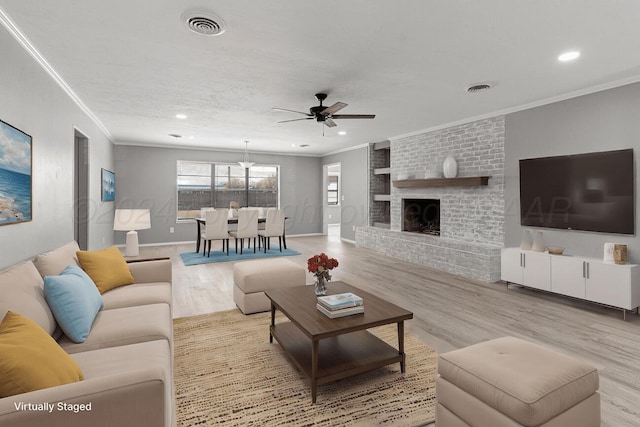 unfurnished living room featuring a brick fireplace, light wood-type flooring, ceiling fan, and crown molding