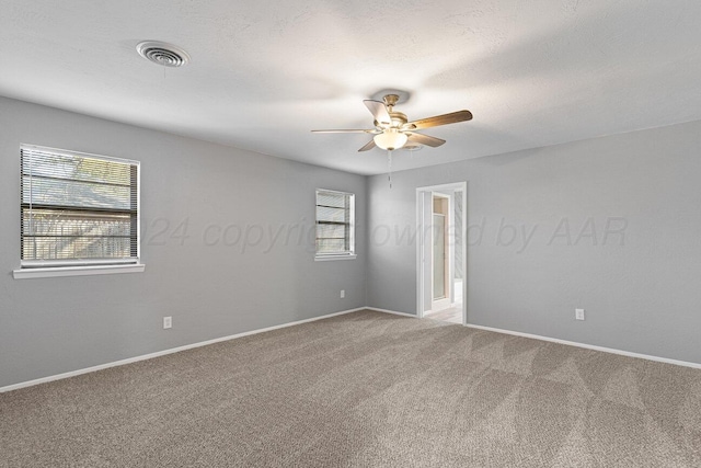 carpeted empty room featuring a wealth of natural light and ceiling fan