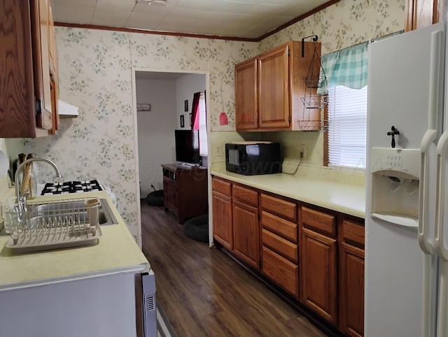 1029 S Farley St, Pampa, TX 79065 - kitchen featuring wallpapered walls, white refrigerator with ice dispenser, black microwave, crown molding, and dark wood-style floors