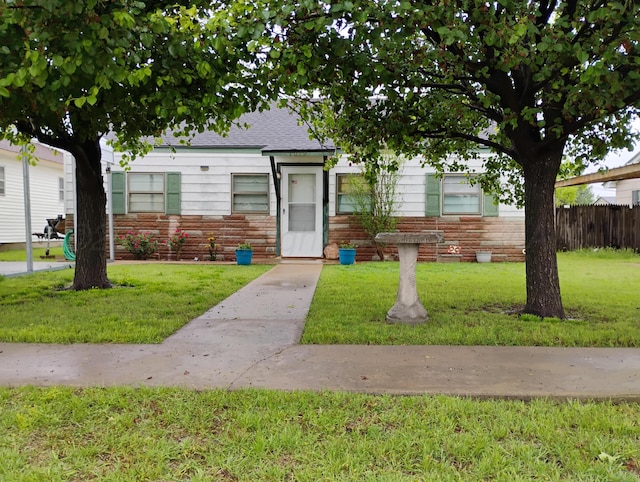 1029 S Farley St, Pampa, TX 79065 - view of front of property featuring a front yard, roof with shingles, stone siding, and fence
