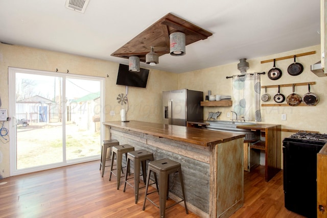 kitchen featuring range with gas cooktop, wood finished floors, stainless steel fridge with ice dispenser, and a sink