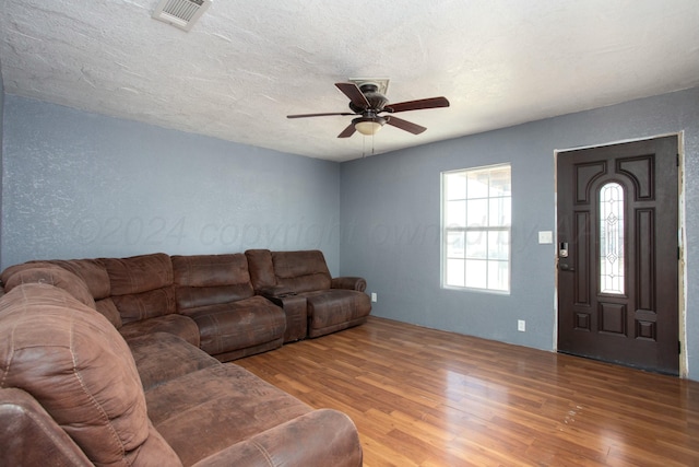 living room with visible vents, a textured ceiling, ceiling fan, and wood finished floors