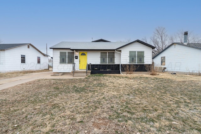 ranch-style home featuring a shingled roof and a front lawn